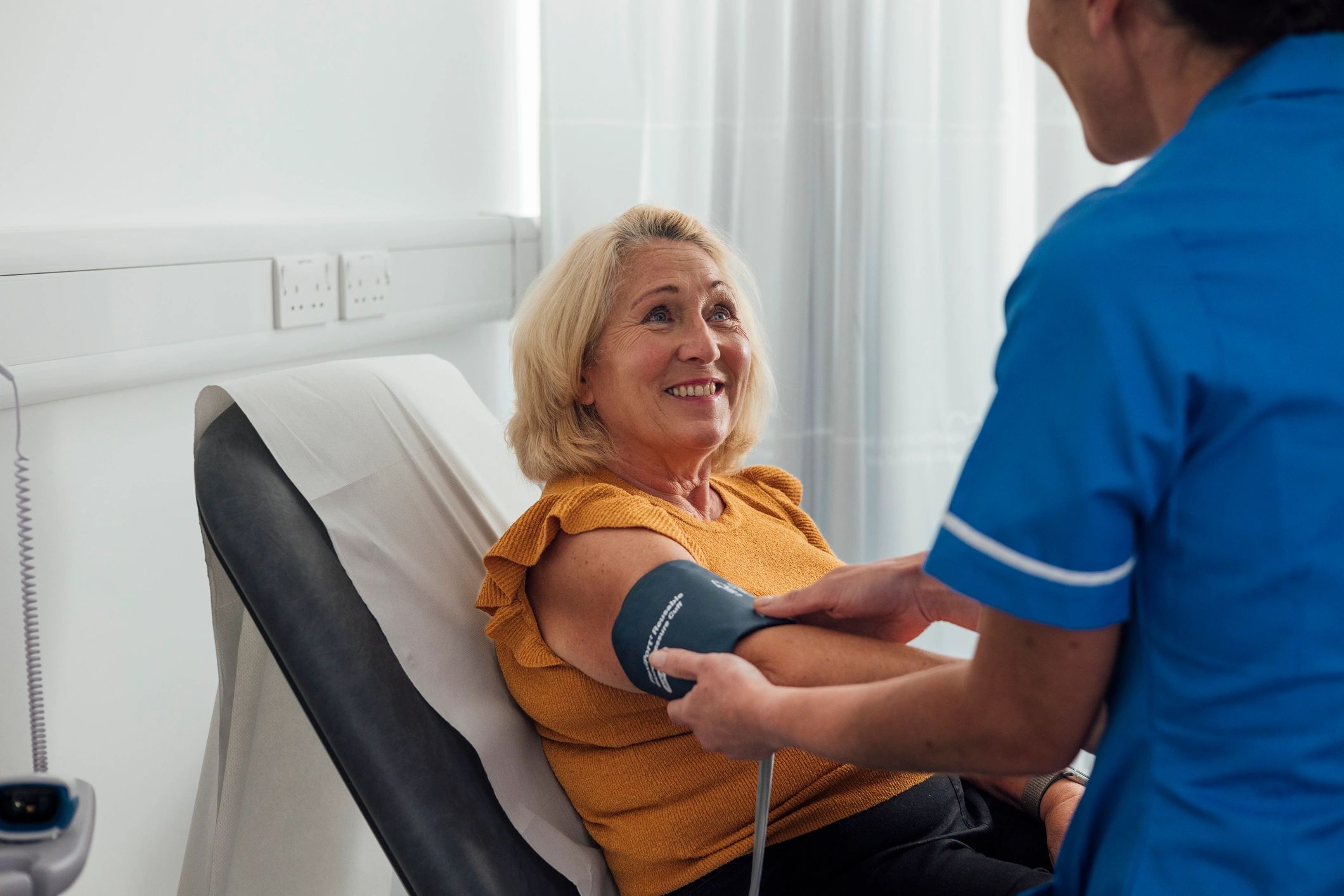 Medical professional taking a patient's blood pressure during a health check